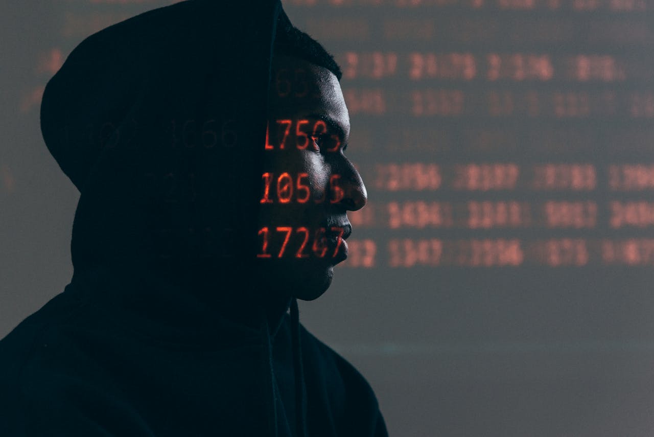 The Art of Drawing Readers In: Your attractive post title goes here Side profile of a man in a hoodie, surrounded by red code, depicting cybersecurity theme.