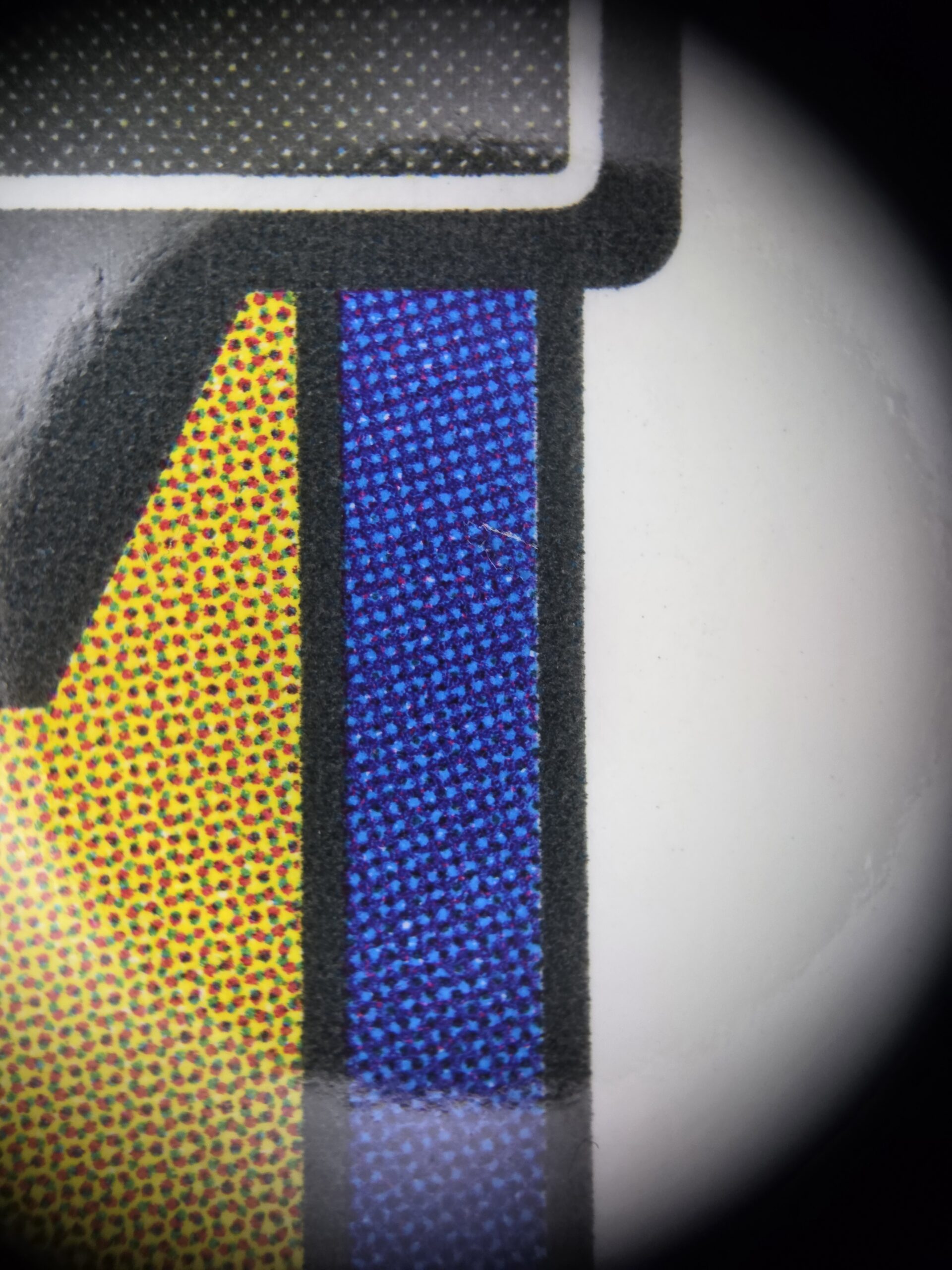 Micro-défaut visible au macro dans le bandeau bleu d'une carte Score
